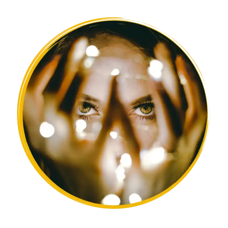 Woman with bright eyes looking through a tangle of light strands in her hands